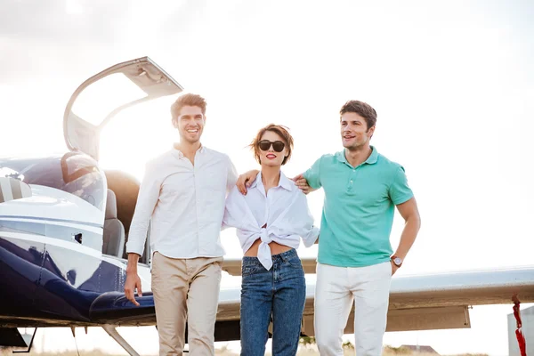 Glückliche junge Freunde, die zusammen auf dem Rollfeld des Flughafens laufen — Stockfoto