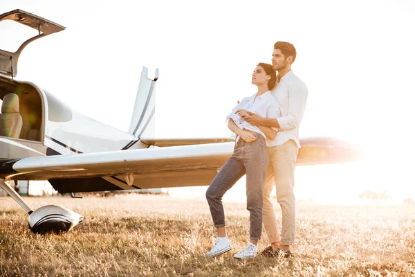 Happy couple on a honeymoon standing at the airplane field — Stock Photo, Image
