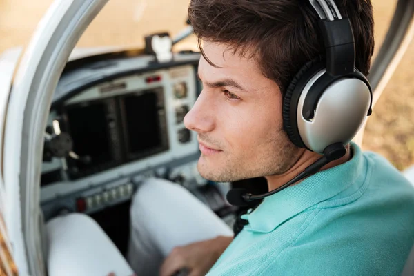 Handsome young man pilot with headset in cabin of plane — Stock Photo, Image