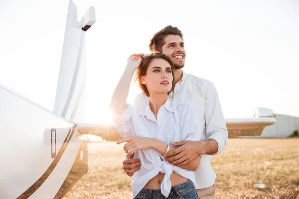 Verliebtes Paar steht zusammen mit Flugzeug im Hintergrund — Stockfoto