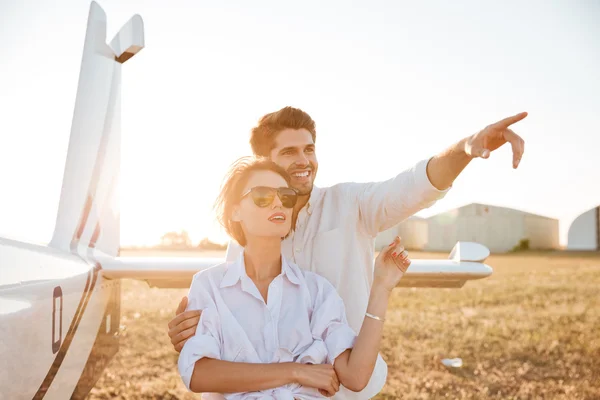 Beautiful couple in love standing together with airplane on background — Stock Photo, Image