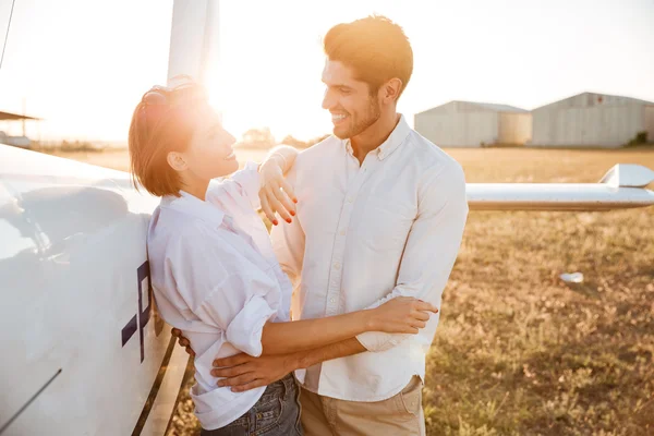 Happy couple on a honeymoon standing at the airplane field — Stock Photo, Image