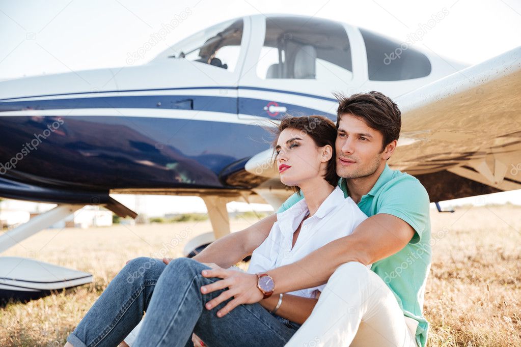 Couple sitting and hugging near small plane