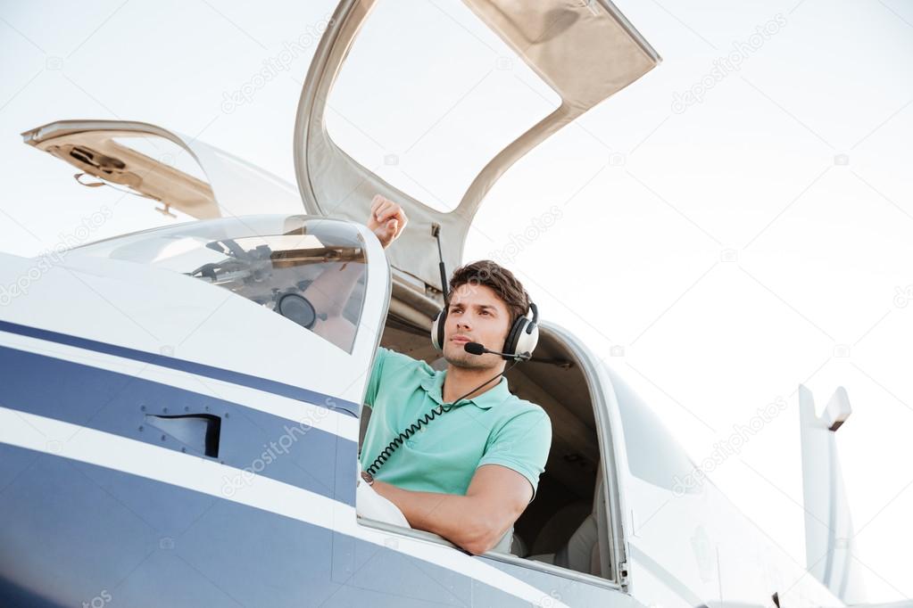 Confident young man pilot in small plane