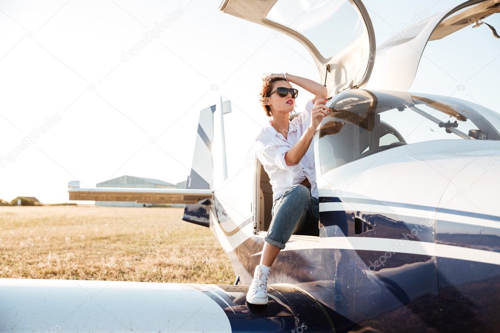 Woman in sunglasses sitting in small private plane