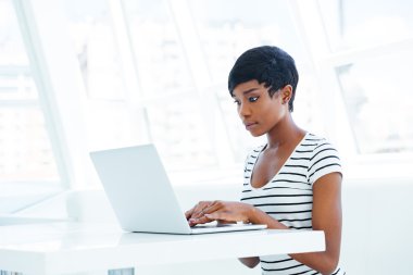 Ciddi Afro-Amerikan işkadını ile laptop masada oturan
