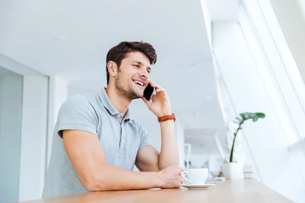Cheerful man talking on cell phone while having coffee break — Stock Photo, Image