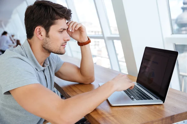 Pensivo jovem empresário sentado com laptop — Fotografia de Stock