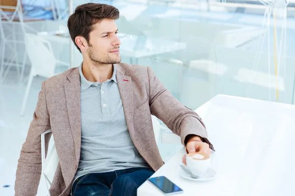 Joven hombre de negocios con chaqueta tomando café en el interior — Foto de Stock