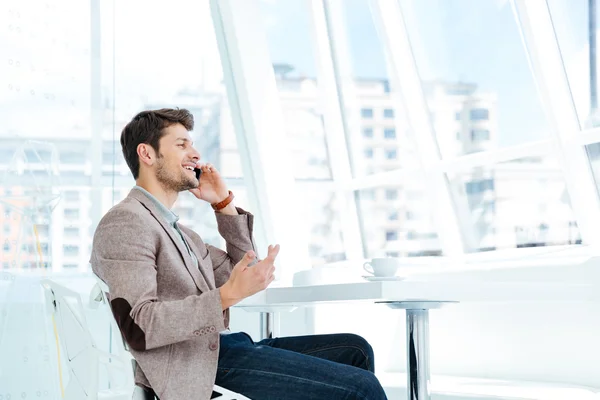 Empresario hablando por teléfono móvil mientras está sentado a la mesa — Foto de Stock