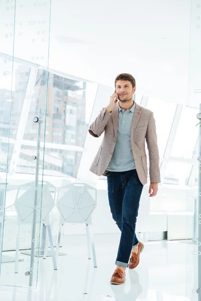 Empresário caminhando no prédio do escritório e falando por telefone — Fotografia de Stock