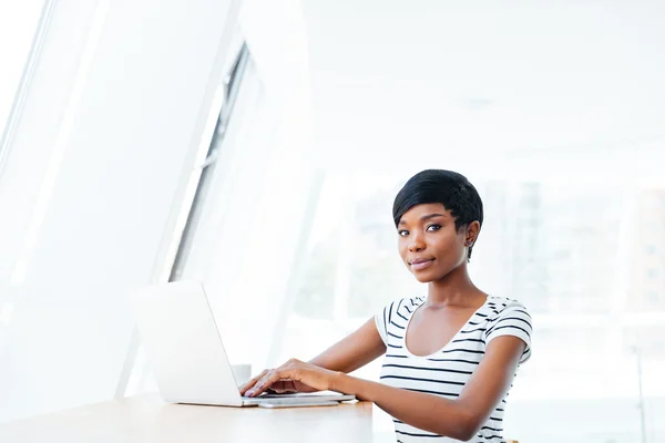 Portrait of a casual smiling african businesswoman using laptop computer — Stock Photo, Image