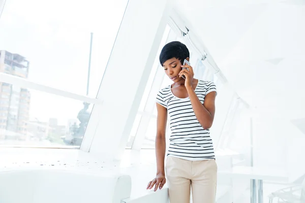 Beautiful businesswoman standing in office and talking on cell phone — Stockfoto
