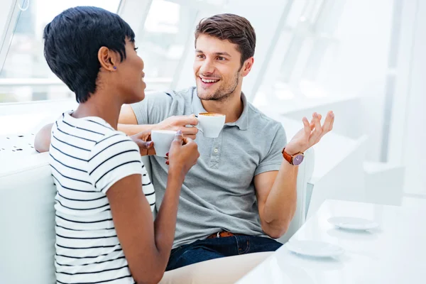 Fröhlicher schöner Mann sitzt und trinkt Kaffee mit seiner Freundin — Stockfoto