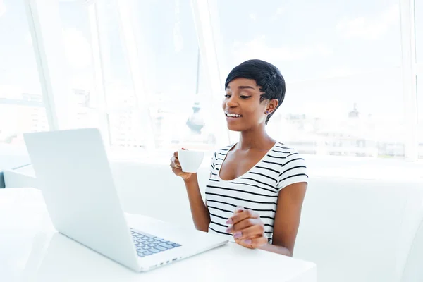 Smiling african american young businesswoman sitting at workplace — Stock Photo, Image
