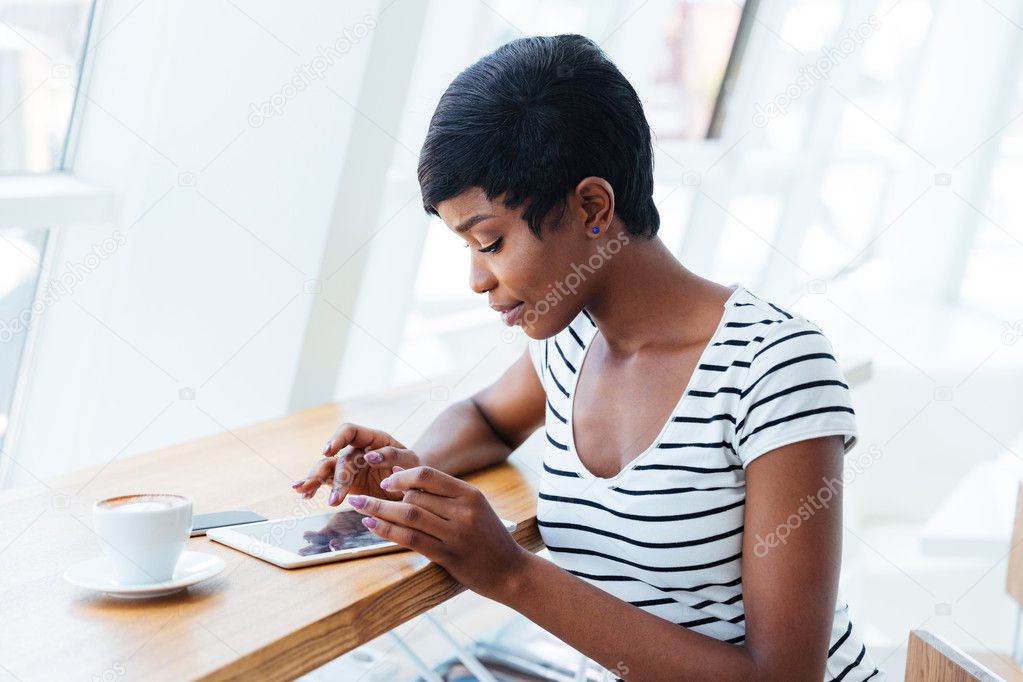 Attractive african businesswoman using tablet amd having coffee break