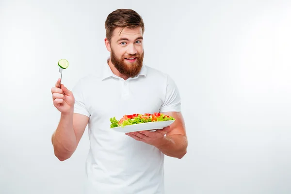 Молодой человек держит вилку, чтобы съесть свежий овощной салат — стоковое фото