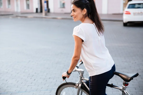 年轻的黑发女人，骑着自行车在城市 — 图库照片