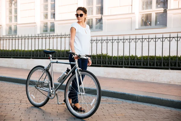 休闲的黑发女人骑自行车的人站在一辆自行车 — 图库照片