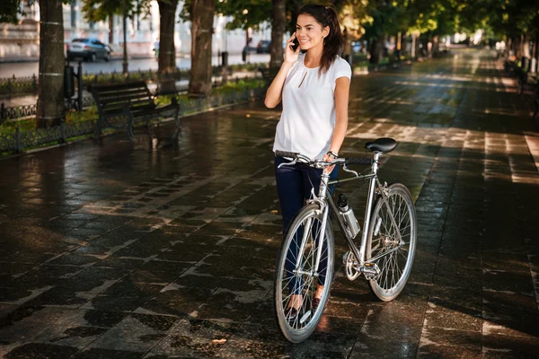 Menina feliz falando ao telefone e andando com bicicleta — Fotografia de Stock