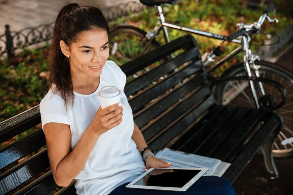 Mujer descansando en el banco con una taza de café en el parque —  Fotos de Stock