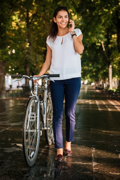 Menina alegre feliz com phpne móvel e bicicleta — Fotografia de Stock