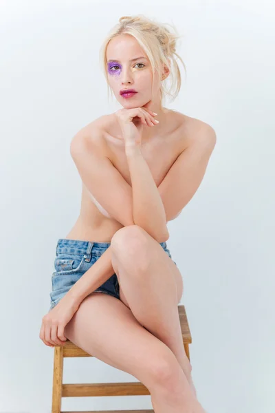 Schöne junge Frau ohne Hemd mit Kunst-Make-up sitzt auf Stuhl — Stockfoto