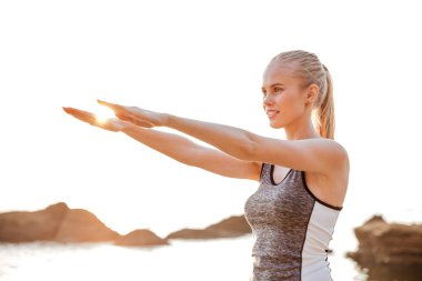 Kumsalda yoga sırasında güzel kadın eller germe egzersizleri