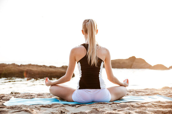 Back view of a young woman sitting in lotus position