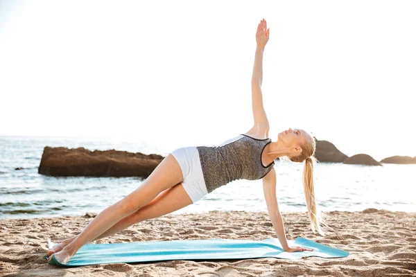 Retrato de una mujer feliz haciendo ejercicios de yoga en la estera — Foto de Stock