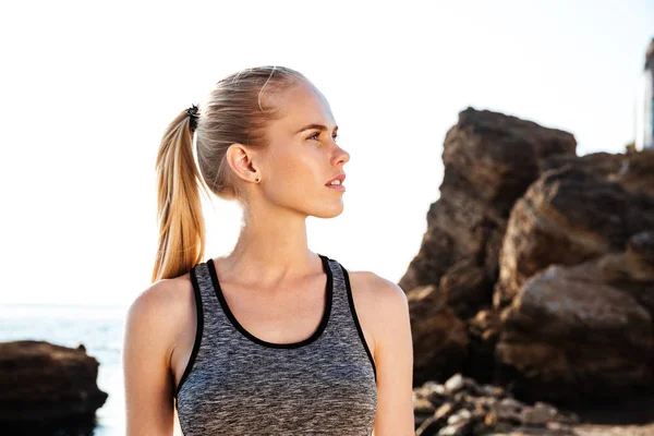 Joven mujer bonita descansando después de entrenar en la playa al atardecer — Foto de Stock