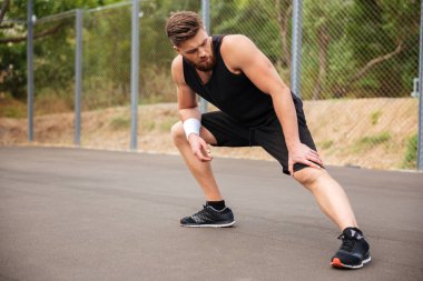 Katta oturan ve bacak germe konsantre erkek atlet