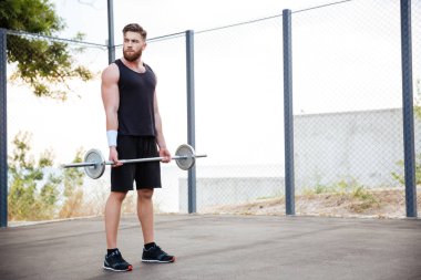 Barbell ile çalışma dışarı konsantre genç adam atlet