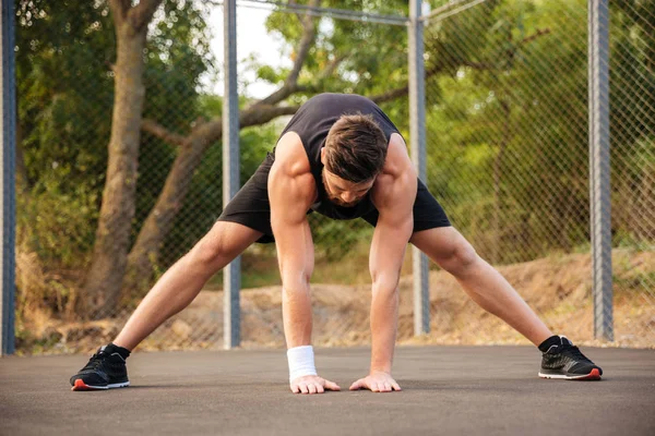 Retrato de um homem de sportswear esticando as pernas ao ar livre — Fotografia de Stock