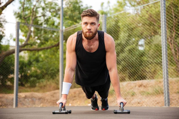 Bonito homem fitness fazendo exercícios push-up com equipamentos esportivos — Fotografia de Stock