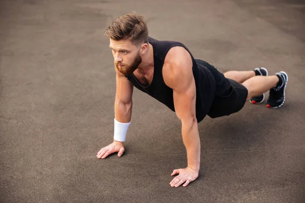 Bonito jovem atleta treinando e fazendo exercícios de prancha ao ar livre — Fotografia de Stock