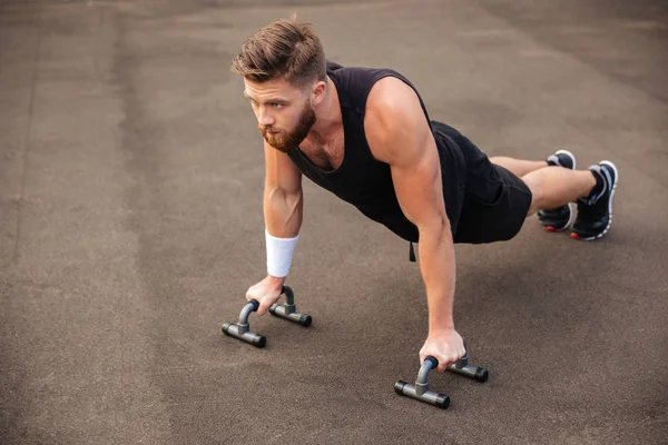 Bonito homem fitness fazendo exercícios push-up com equipamentos esportivos — Fotografia de Stock