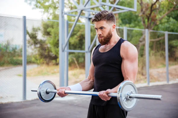 Confiante jovem fitness homem fazendo exercícios com barbell — Fotografia de Stock