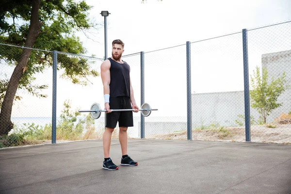 Barbell ile çalışma dışarı konsantre genç adam atlet