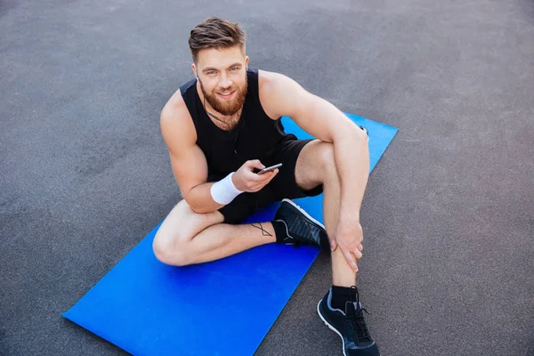 Jovem desportista feliz descansando e usando telefone celular — Fotografia de Stock