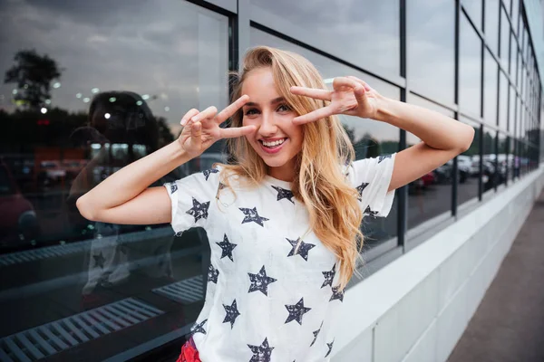 Sarışın genç kadın gösteren v işareti açık havada duran süre gülümseyen