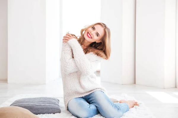 Donna con maglione e rossetto rosso seduta sul tappeto — Foto Stock