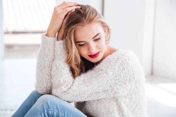 Nachdenkliche blonde junge Frau mit Pullover und rotem Lippenstift — Stockfoto