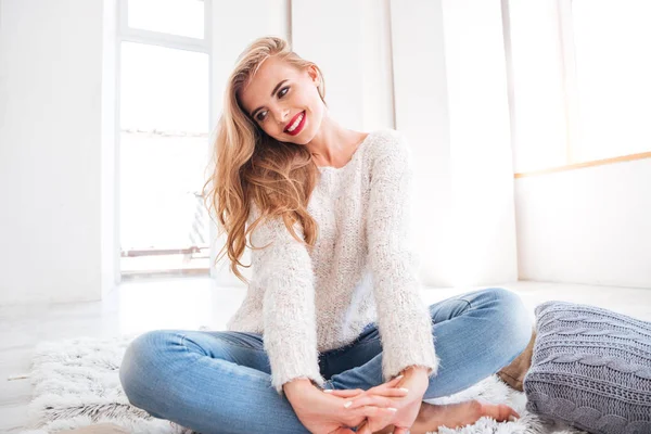 カーペットの上に座ってセーターで美しい若い女性 — ストック写真