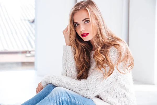 Attractive woman wearing sweater and red lipstick looking at camera — Stock Photo, Image