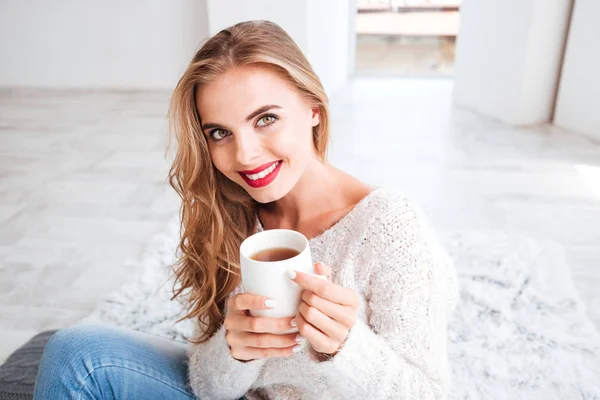 Sonriente chica atractiva en suéter sosteniendo taza de té — Foto de Stock