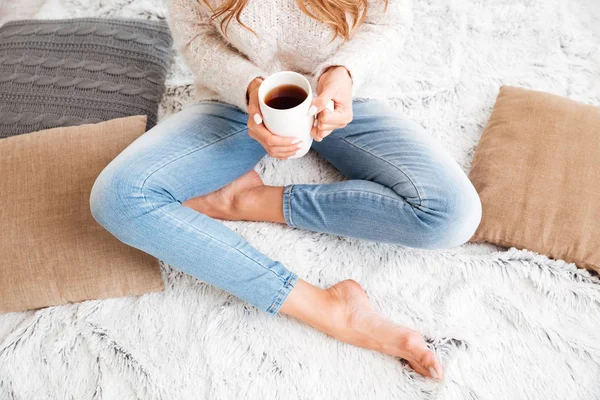 Mujer sosteniendo taza de té mientras está sentado con las piernas cruzadas —  Fotos de Stock