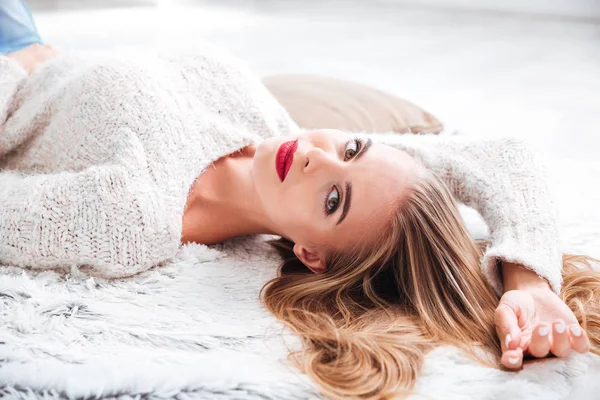 Attraktive Frau im Pullover zu Hause auf dem Teppich liegend — Stockfoto