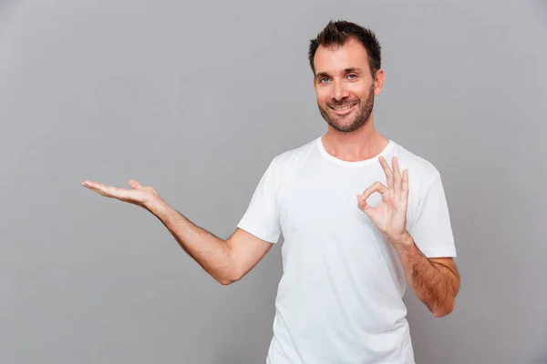 Hombre con camisa y pantalones grises sosteniendo copyspace en la palma — Foto de Stock