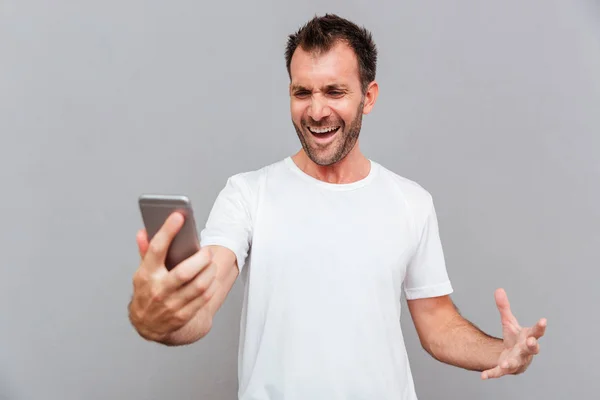 Hombre casual enojado sosteniendo teléfono inteligente — Foto de Stock